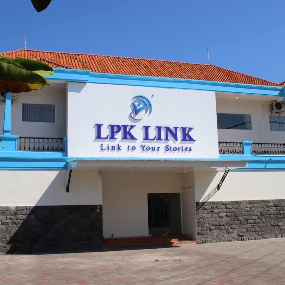 第1校舎の正面。赤い瓦屋根と水色の手すりの建物に、LPK LINK の白い看板